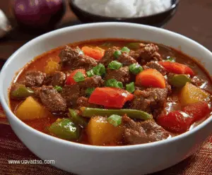 Delicious Filipino Beef Caldereta served with rice, featuring tender beef chunks, savory sauce, vegetables, and garnished with cheese and olives