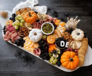 Festive Halloween charcuterie board with spooky-themed cheese, cured meats, Halloween candies, and decorative ghoulish accents for a fun party platter.