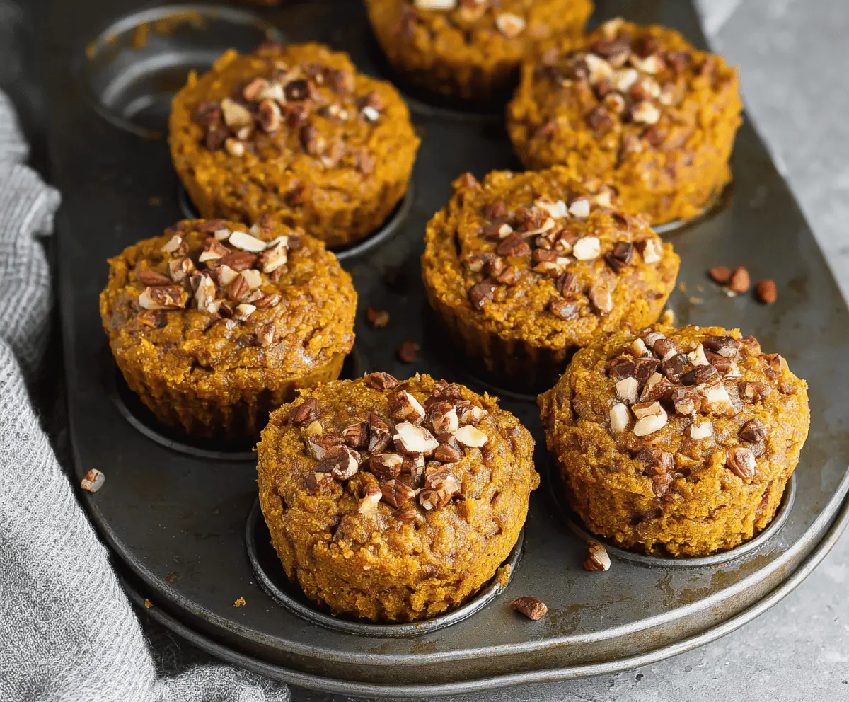 Delicious homemade pumpkin almond flour muffins on a white plate with fresh pumpkin and almonds in the background