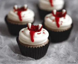 Vampire Bite Cupcakes with red filling and spooky Halloween-themed decorations on a festive plate